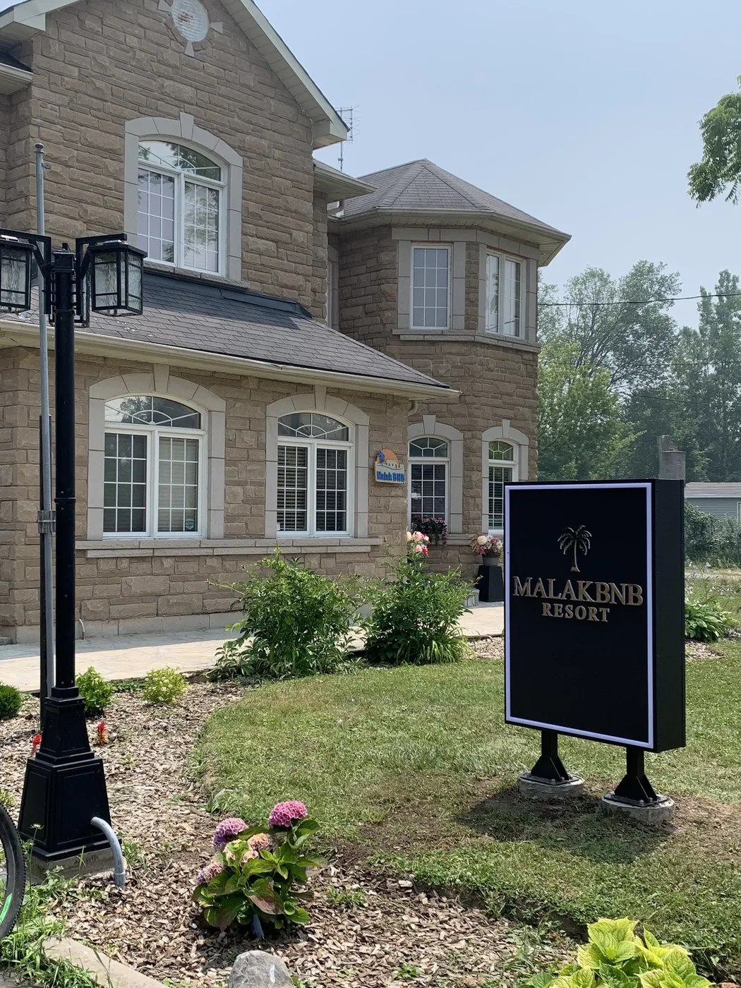 Stone exterior of Malak BnB Resort in Crystal Beach with the branded signboard in the front garden